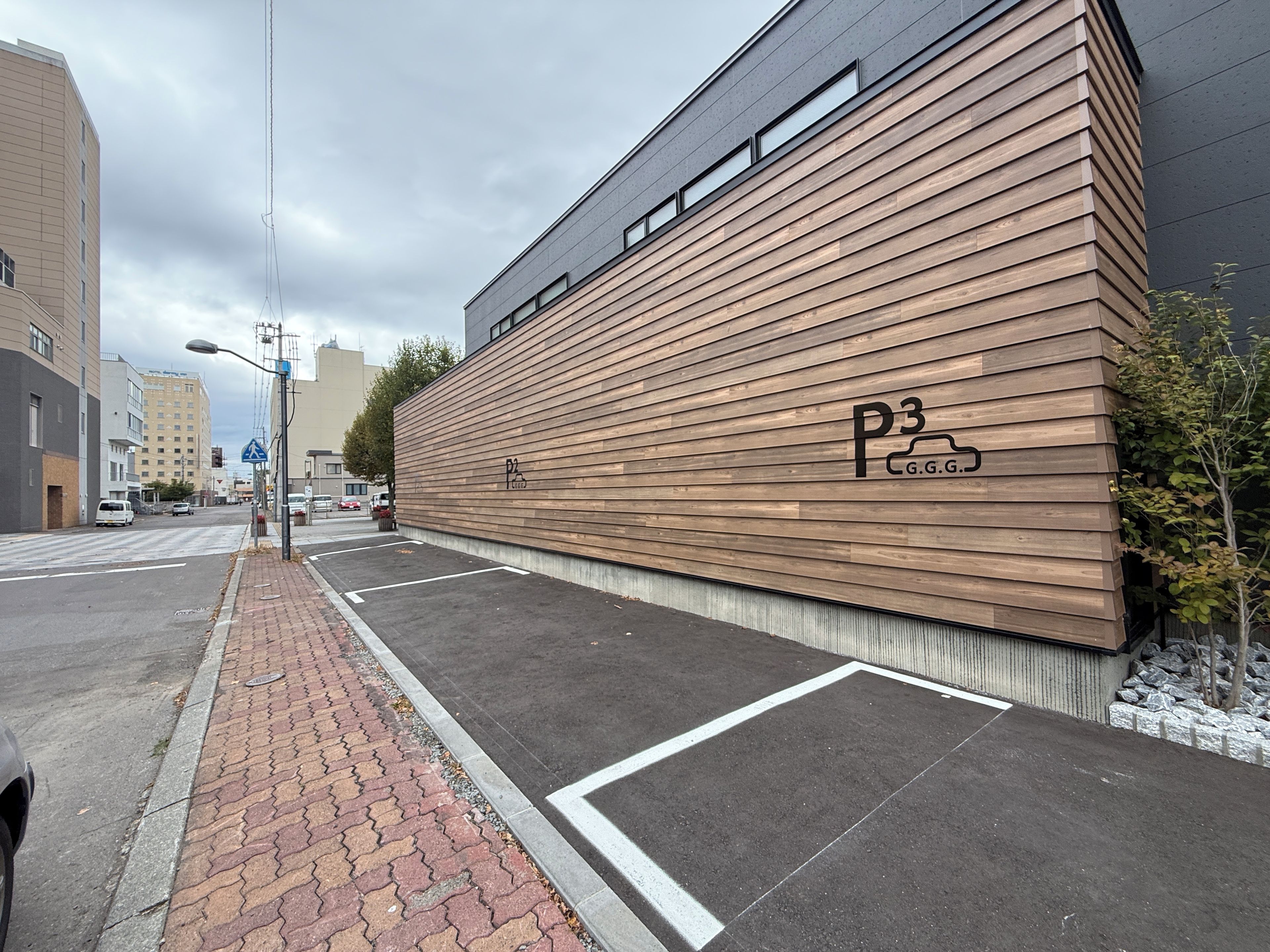Un edificio moderno con fachada de madera y un estacionamiento con espacios delimitados.