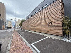 Un edificio moderno con fachada de madera y un estacionamiento con espacios delimitados.