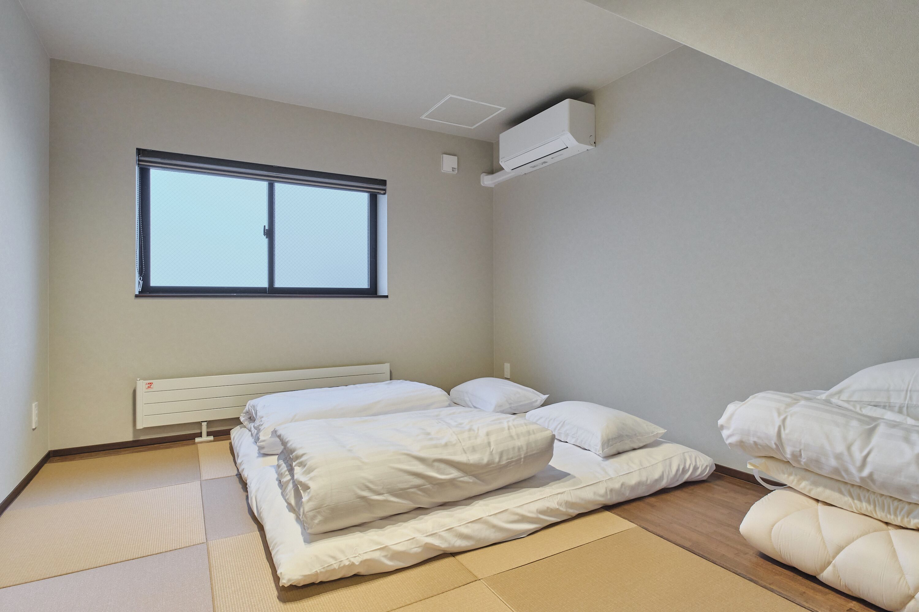 Een slaapkamer met een bed, een raam en een airconditioning.