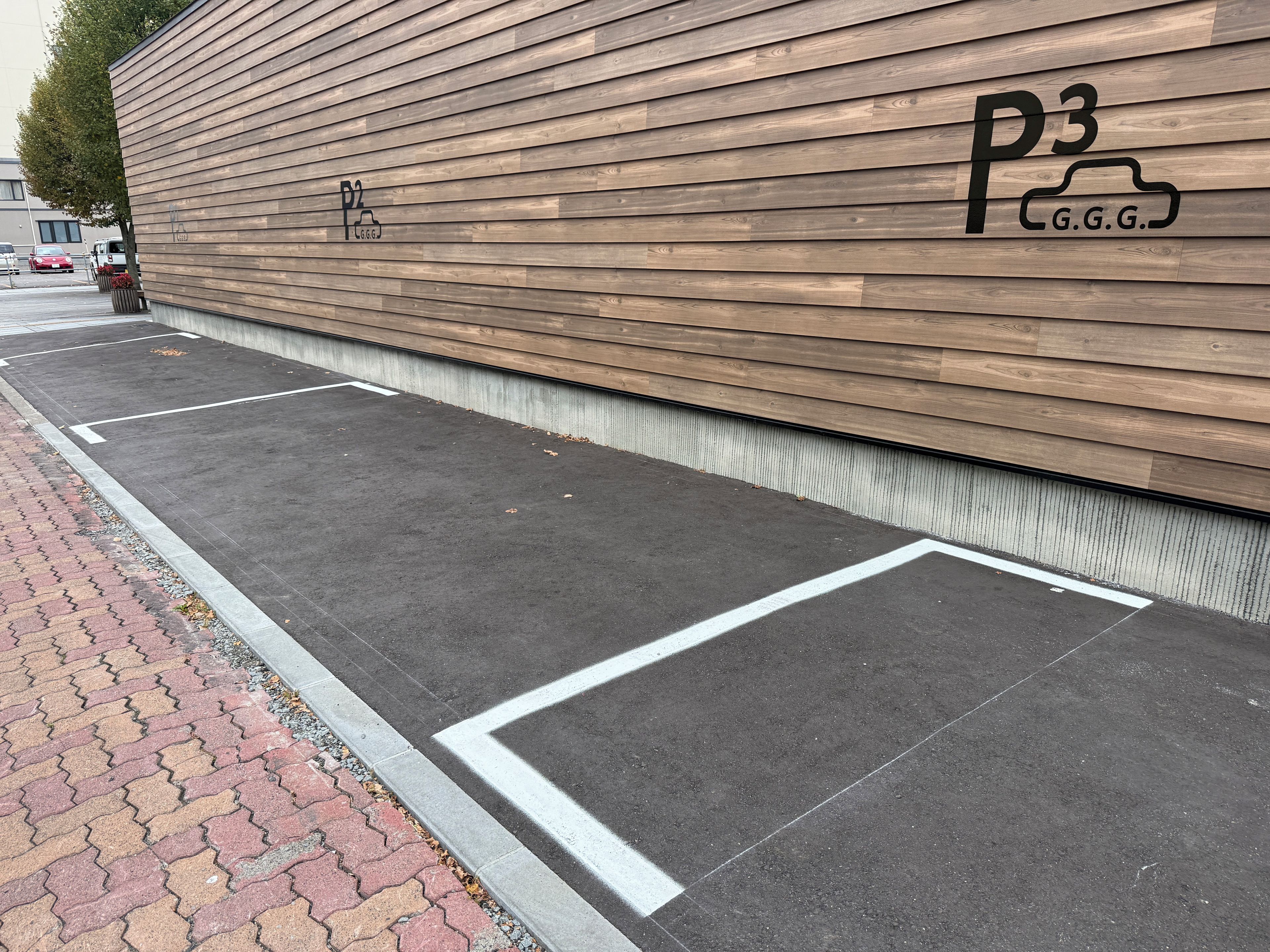 A parking area with marked spaces and a wooden wall with signage.