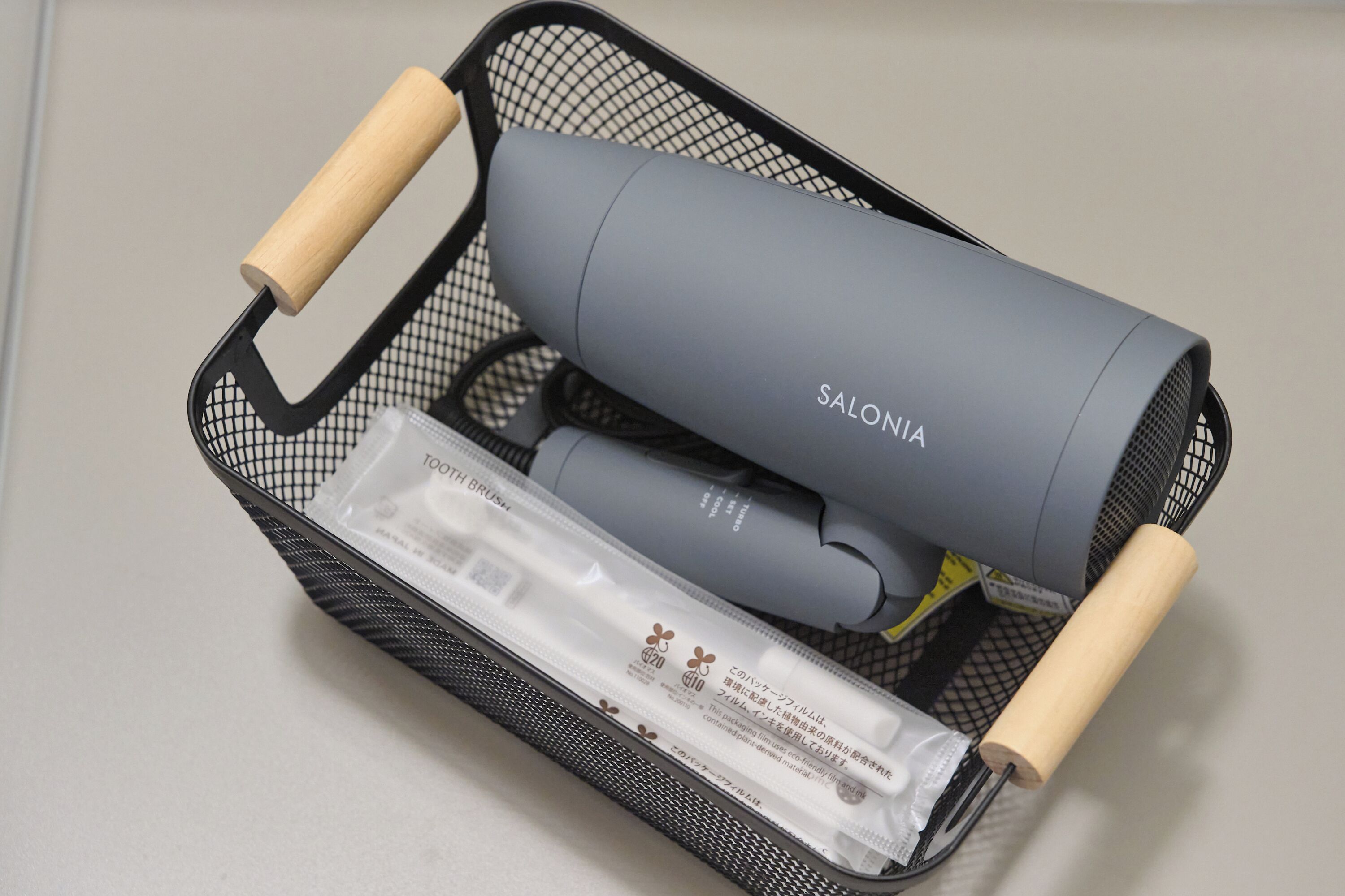 A black mesh bag containing a grey cylindrical object labeled 'SALONIA,' a white rectangular object, and a small white packet.