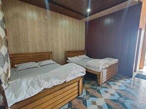 A room with two wooden beds, a patterned floor, and a wooden ceiling. - Jay jyoti resorts & caffe (Ukhimath)
