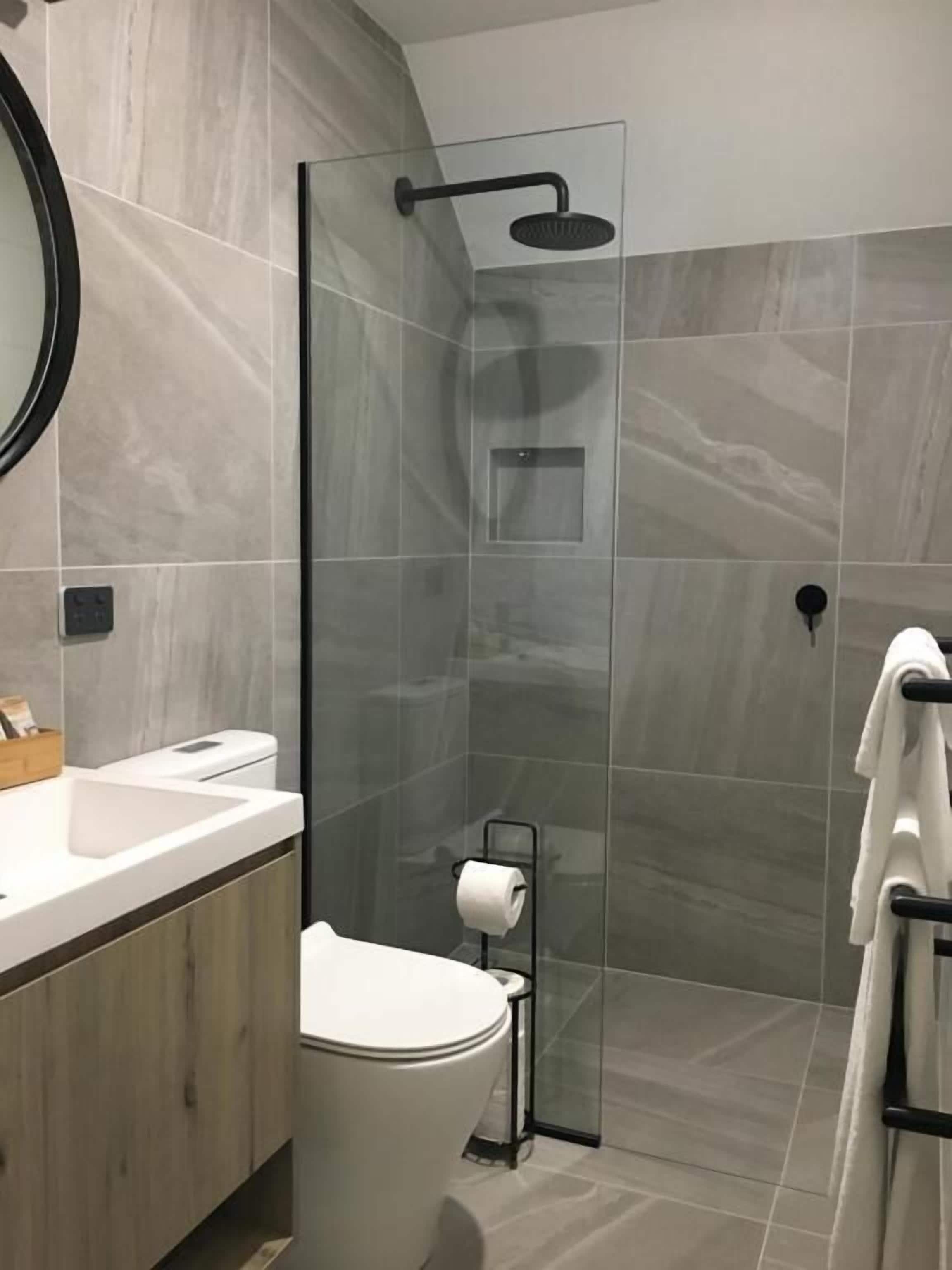 Een moderne badkamer met een douchecabine van glas, een toilet en een wastafel.