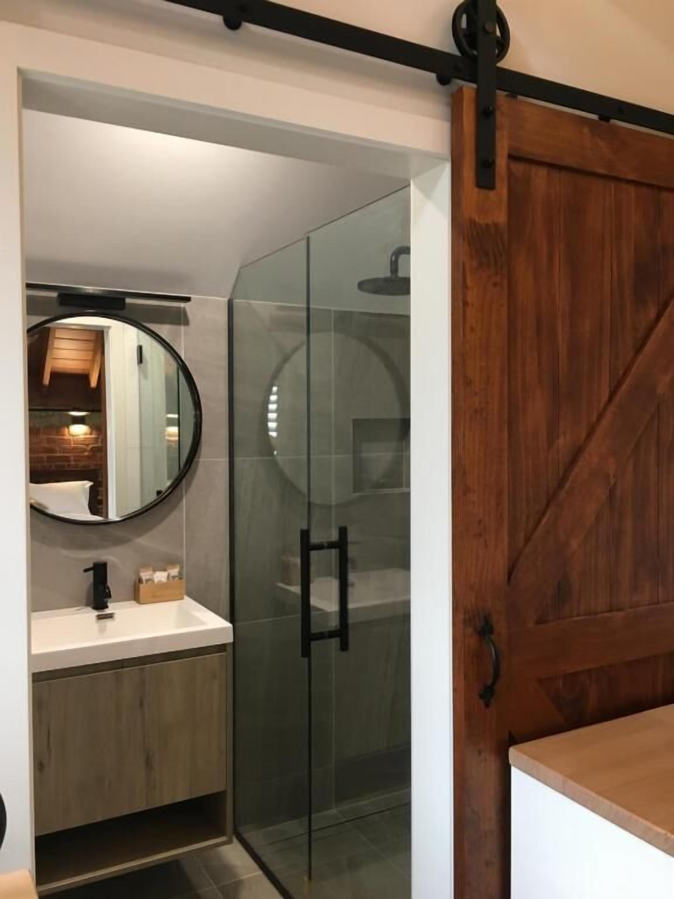 A modern bathroom with a glass shower enclosure, a wooden vanity, and a large mirror.