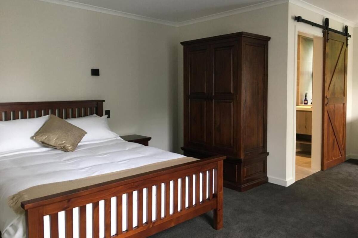 Un dormitorio con cama de madera, una mesita de noche, un armario y una puerta corredera que da a un vestidor.
