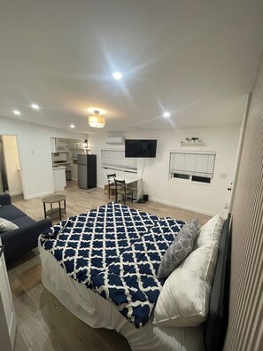 Ein Schlafzimmer mit Bett, Schreibtisch, Stuhl und einem an der Wand befestigten Fernseher.