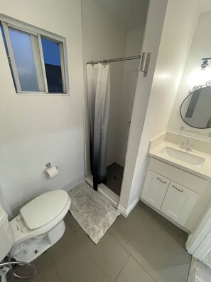 Ein Badezimmer mit Toilette, Dusche, Waschbecken und Spiegel.