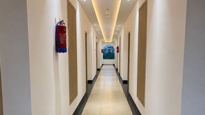 A hotel corridor with a straight path, doors on both sides, and a fire extinguisher mounted on the wall. - Shri ji vilas (Vrindavan)