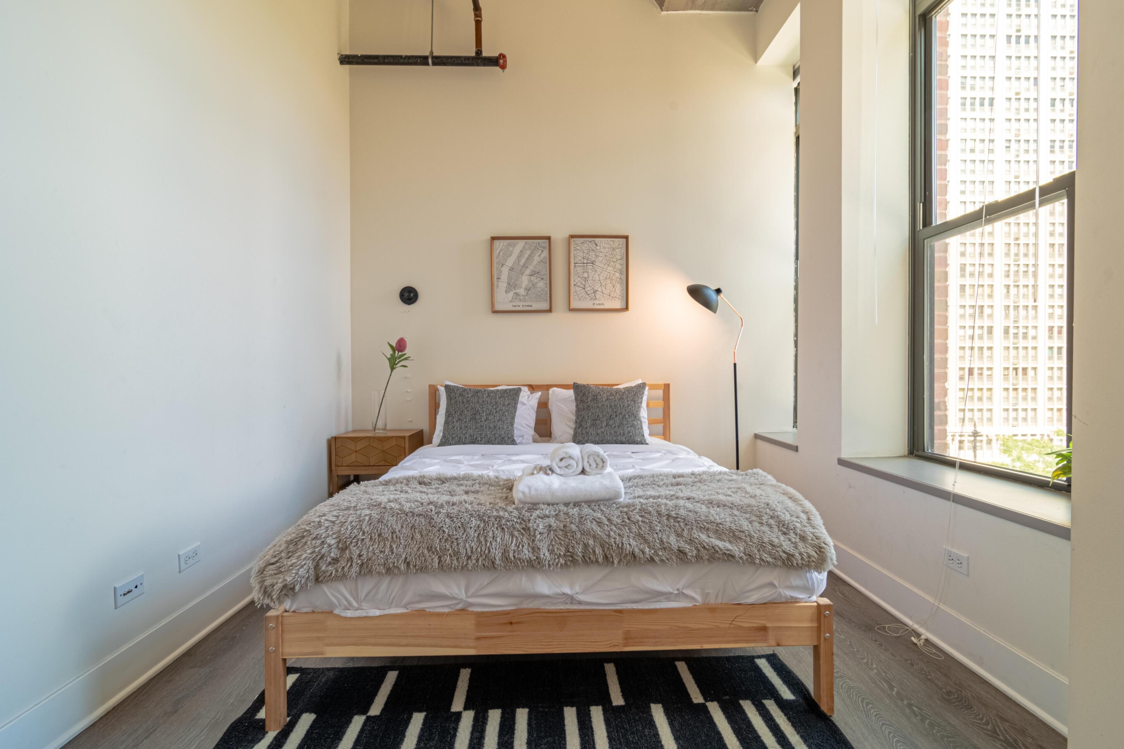 Una cama bien hecha con un edredón mullido, un cabecero de madera y dos cuadros en la pared.