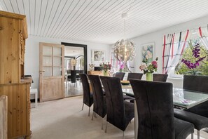 A dining area with a glass table, black chairs, a wooden cabinet, and a view of the outdoors through a window. - Spacious holiday home near Limfjord and nature (Øster Assels)