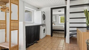 Un espace buanderie comprenant un lave-linge, un étendoir et un évier.