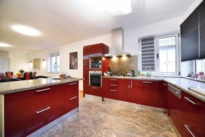 A modern kitchen with red cabinets, a microwave, and a stove.
