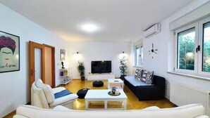 A modern living room with a white sofa, a black sofa, a white coffee table, and a TV.