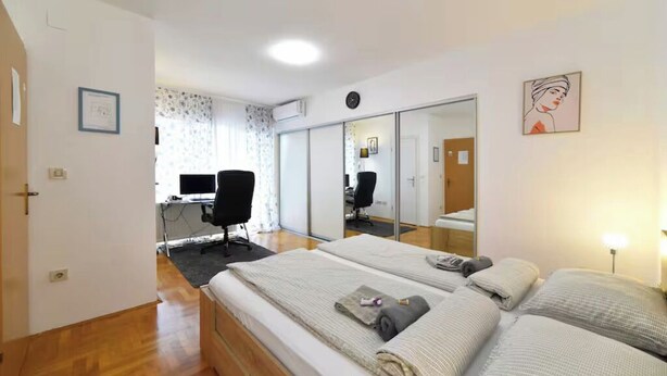 A bedroom with a bed, a desk, and a mirror.