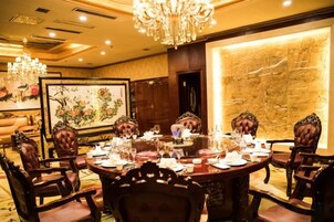 Un comedor formal con una mesa redonda, sillas ornamentadas y una araña.