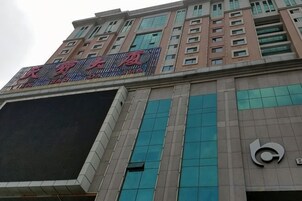 A multi-story building with a large digital display screen and a prominent sign with Chinese characters.
