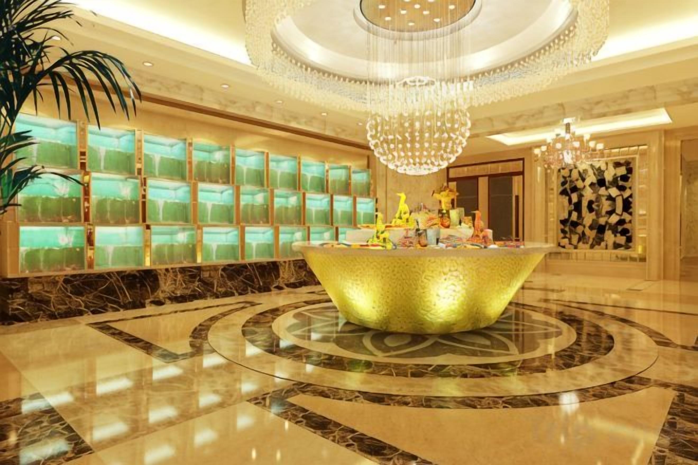 A lobby with a central reception desk, a large chandelier, and a patterned floor.