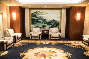 Una habitación con un cuadro grande, dos sillones, una mesita y una alfombra de motivos florales.