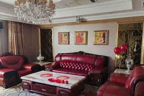 A room with a red leather sofa, a marble coffee table, and a chandelier.