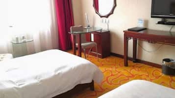 Una habitación de hotel con dos camas, un escritorio, una silla, un televisor y una cortina roja.
