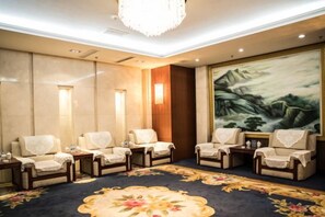 A room with four armchairs, a carpet with floral patterns, a large painting of mountains, and a chandelier. - Tianbao Hotel (Fushun)