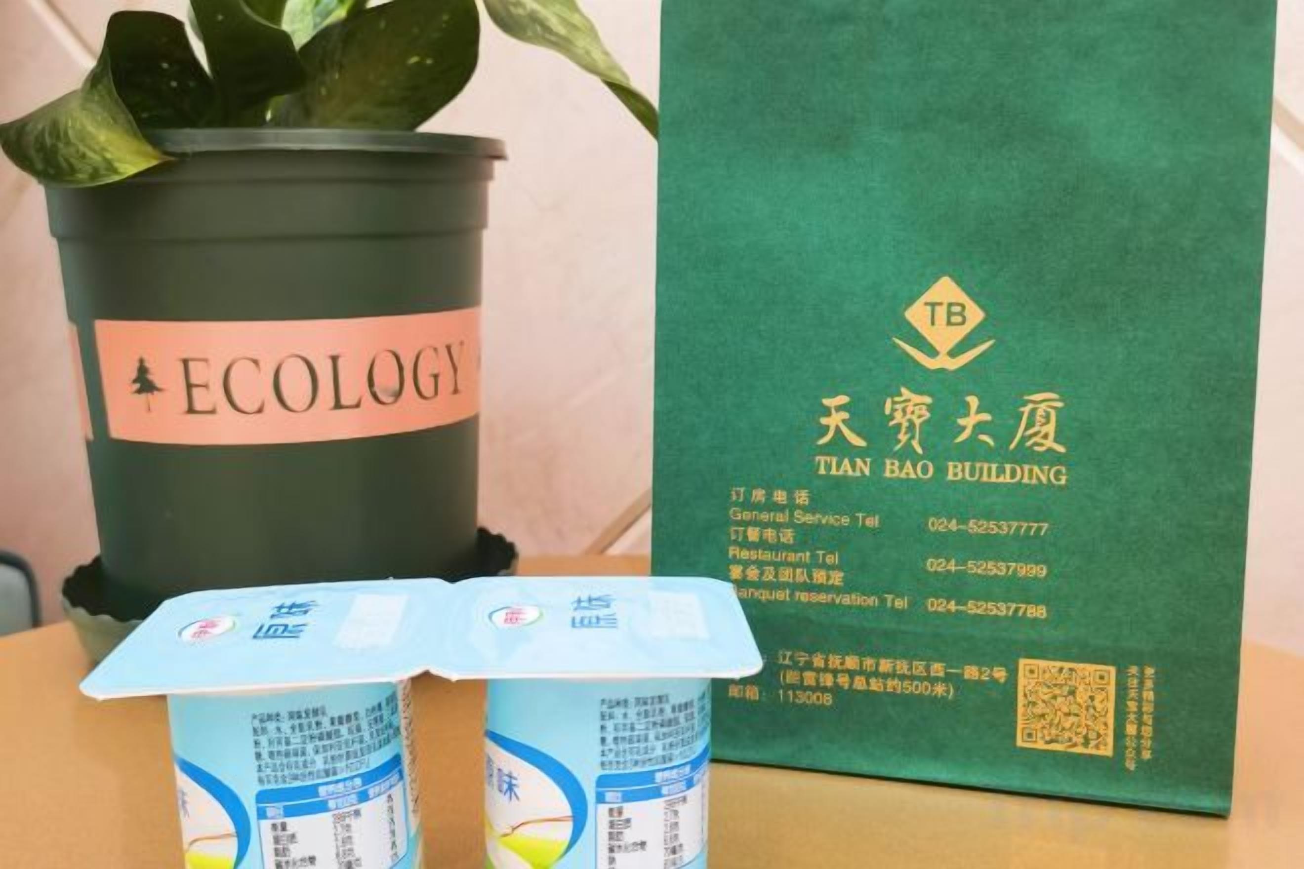 A potted plant labeled 'ECOLOGY' and a green brochure for Tian Bai Building.
