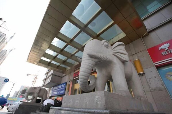Una gran estatua de elefante frente a un edificio con techo de vidrio y un letrero con caracteres chinos.