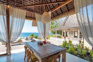 An outdoor dining area with a wooden table, chairs, and a view of the sea. - Dolce Vita  (Penida Island)
