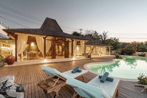 A resort with a pool, wooden deck, and a covered area with curtains. - Dolce Vita  (Penida Island)