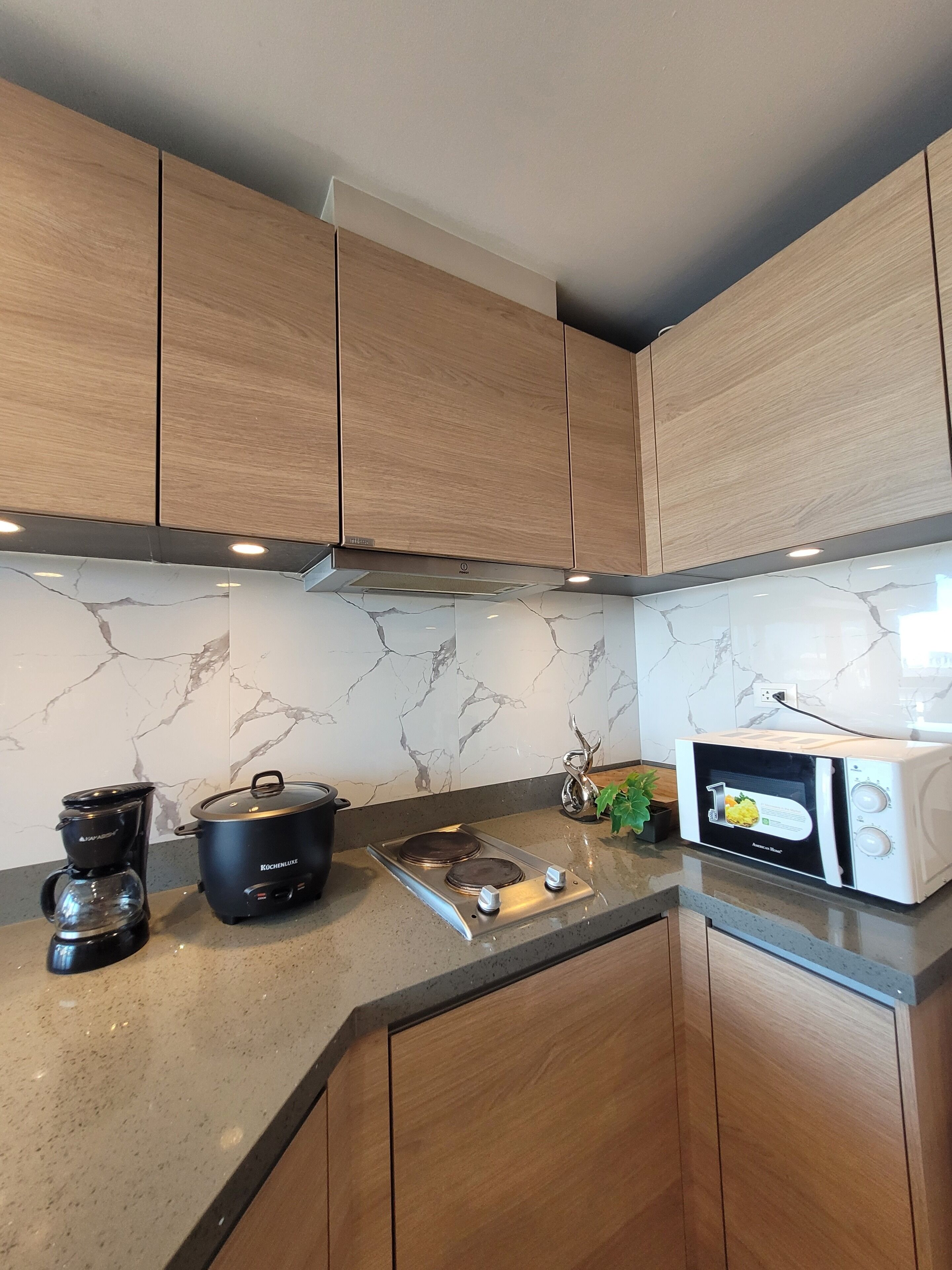 A kitchen with wooden cabinets, a coffee maker, a slow cooker, and a microwave.