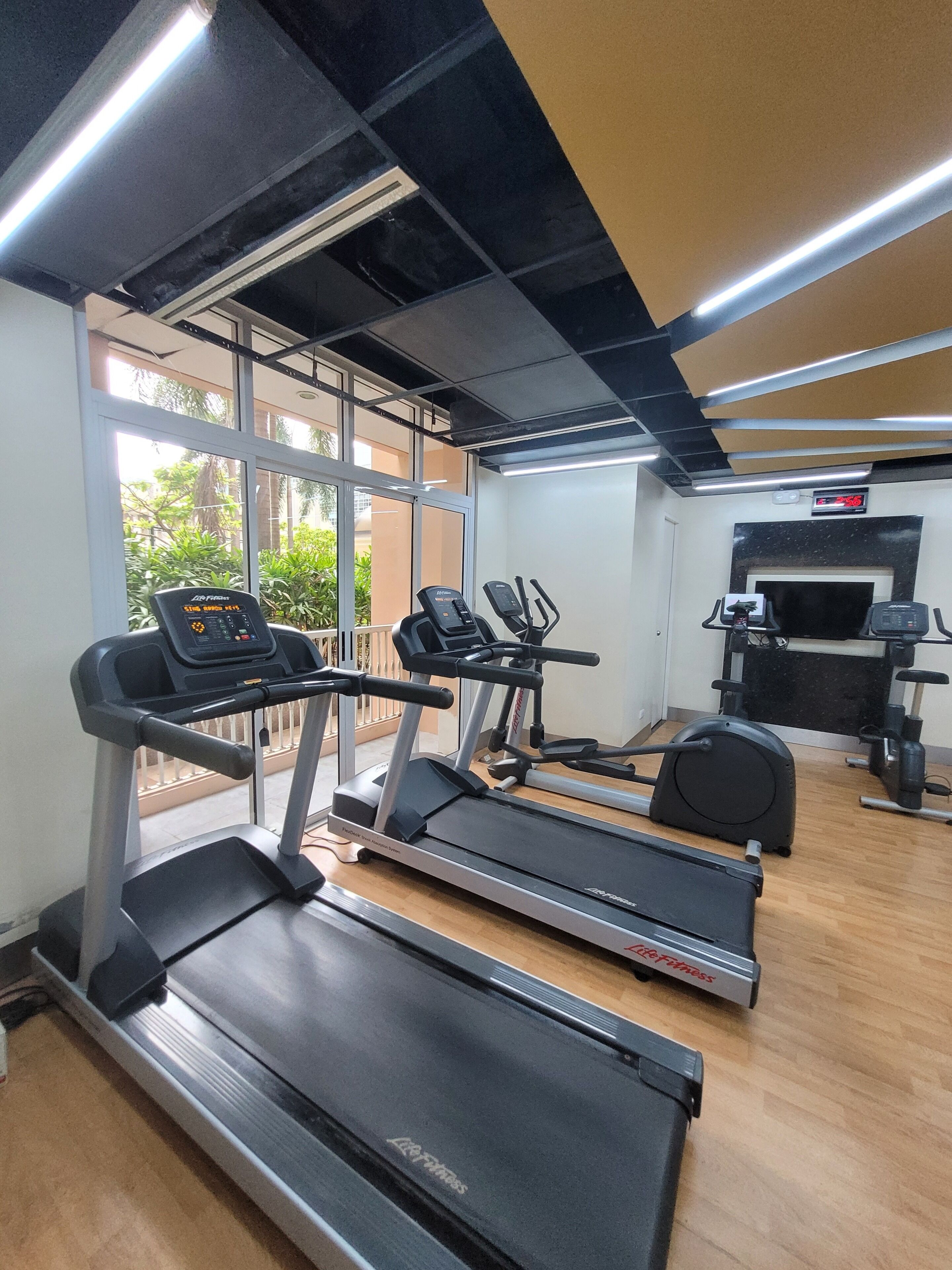 A gym with treadmills, elliptical machines, and a weight bench.