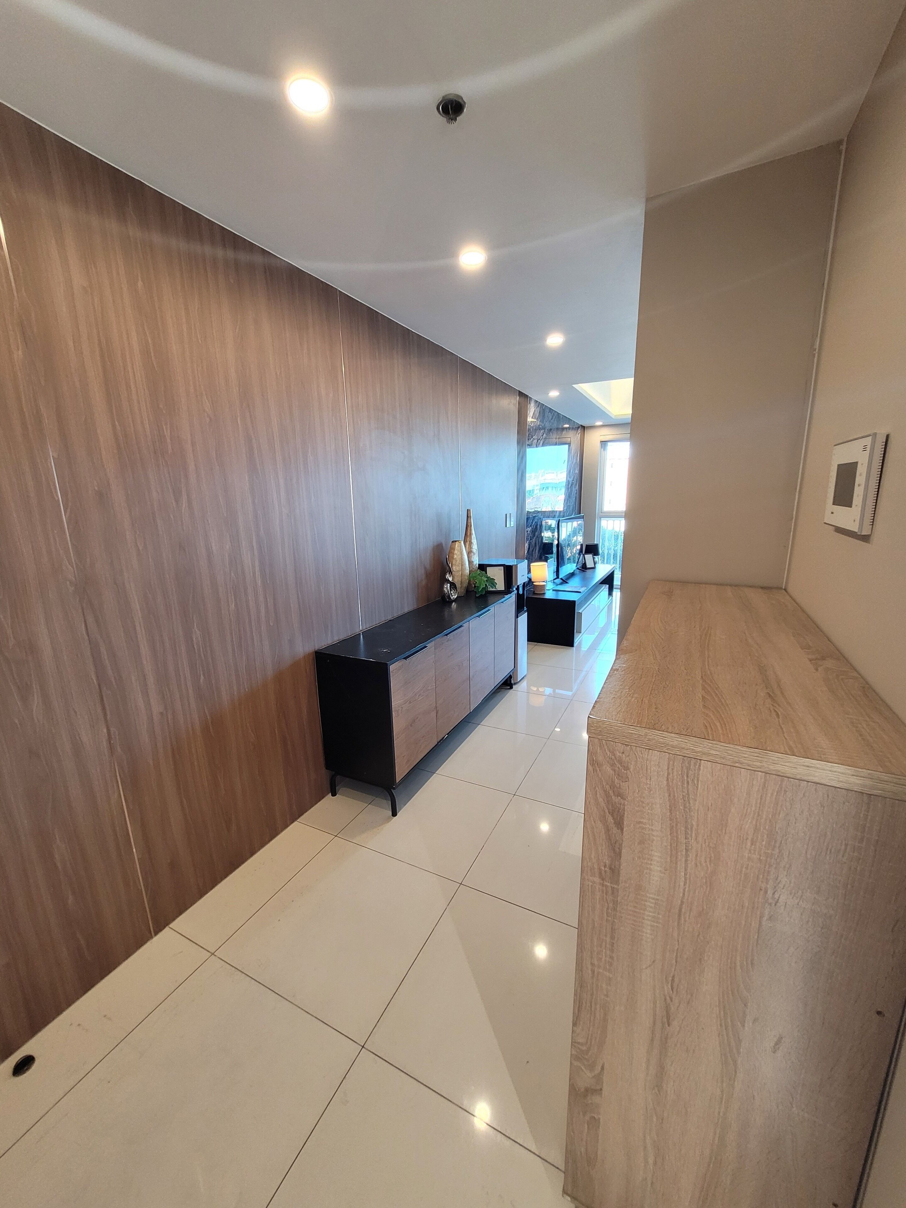 Un intérieur moderne avec un mur en bois, une console noire et un sol carrelé.