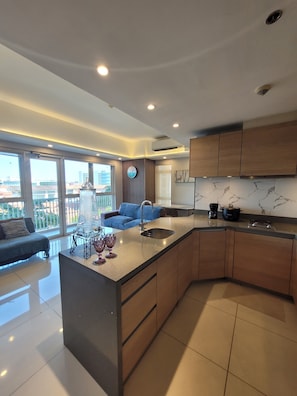 Una cocina moderna con una isla central, armarios de madera y un amplio ventanal con vistas a un balcón.