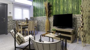 Una sala de estar moderna con televisor, asientos, una zona de comedor y una pared de bambú.