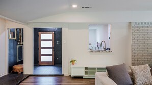 Ein modernes Wohnzimmer mit einer Couch, einem Couchtisch, einem Kamin und einer Tür zu einem anderen Raum.