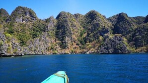 A boat on a calm sea with rocky cliffs in the background.