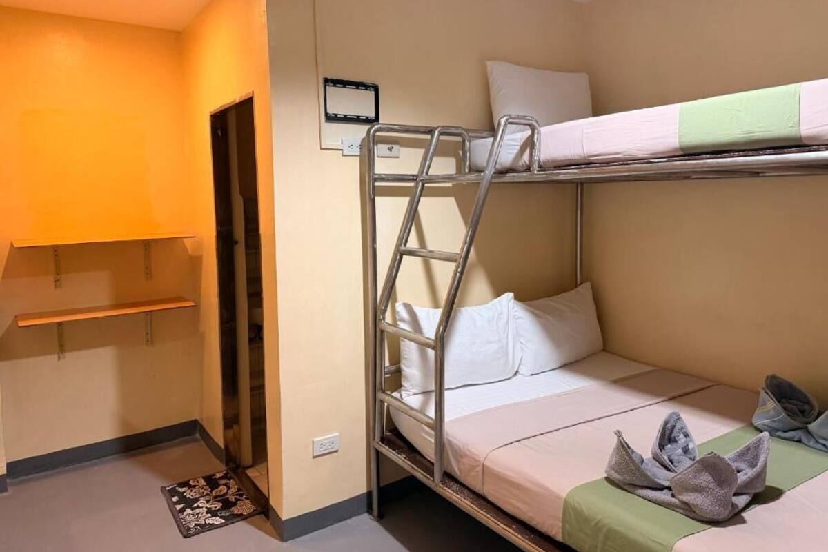 Habitación con literas, una mesita de noche y una pequeña estantería.