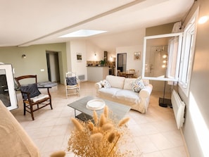 A living room with a sofa, a coffee table, and a chair. There is a dining area with a table and chairs.