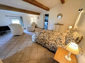 A bedroom with a bed, a nightstand, a chair, a dresser, and a window.
