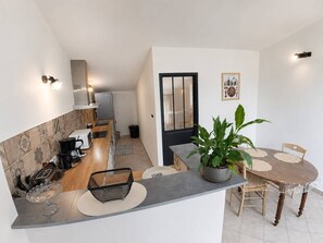 Eine kompakte Küche mit Mikrowelle, Toaster und Kaffeemaschine. Ein Essbereich mit Tisch und Stühlen ist zu sehen.