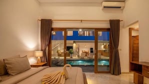 Quarto de hotel com uma cama, luminária de cabeceira, toalha em forma de cisne, piscina e vista para a área da piscina.