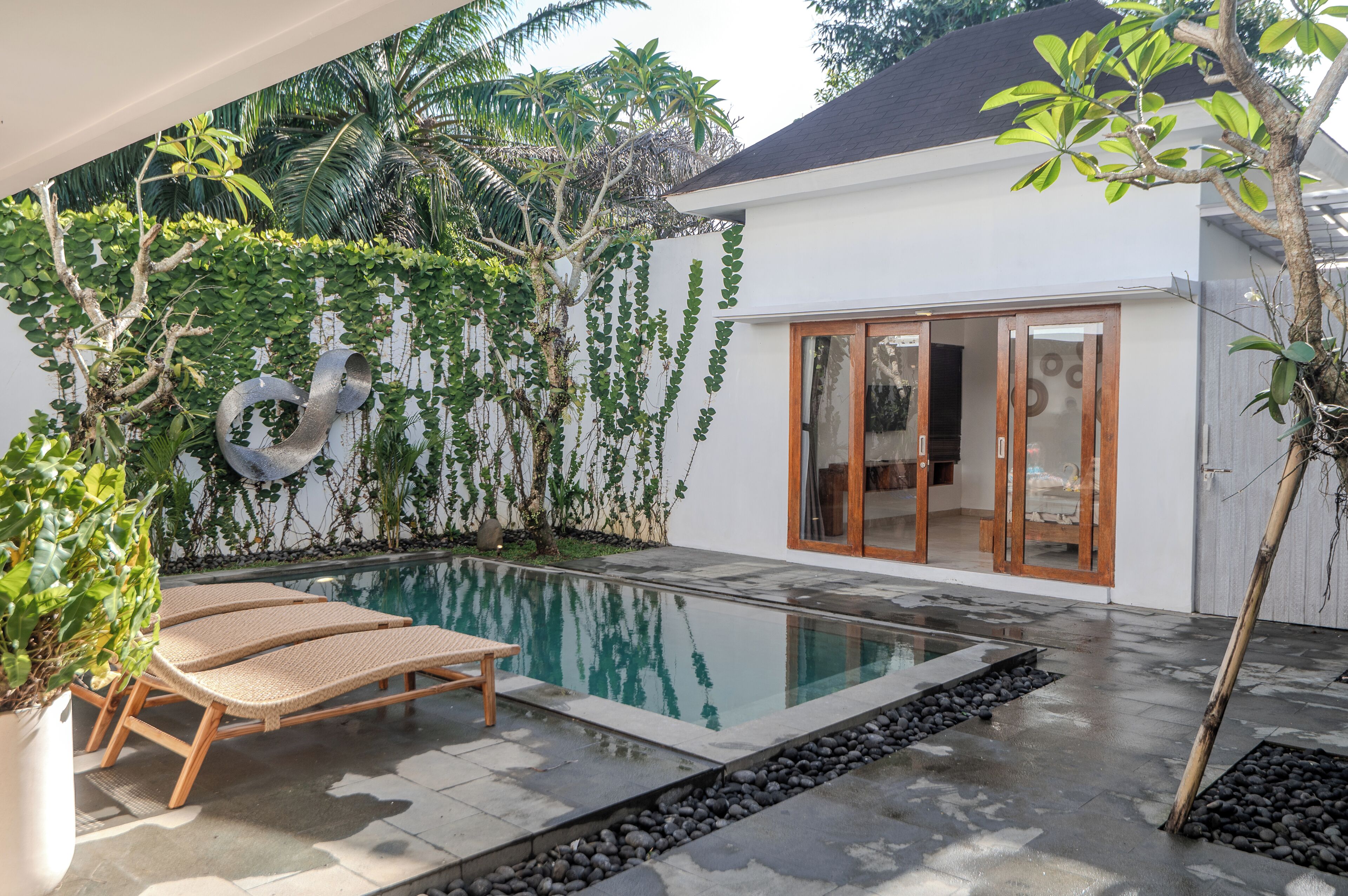 A swimming pool with lounge chairs, a wooden deck, and a white building with glass doors.