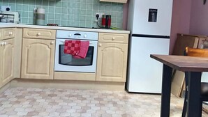 A kitchen with wooden cabinets, a white refrigerator, a stove, and a tiled backsplash.