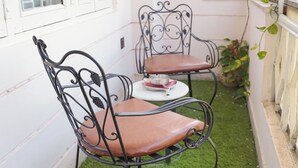 A small outdoor seating area with two metal chairs and a table, surrounded by white walls and a window. - Parkside Haven 3BHK By Avinal (Jaipur)