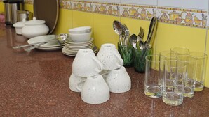 A kitchen with white cabinets, a tiled backsplash, and various kitchenware items on the counter. - Parkside Haven 3BHK By Avinal (Jaipur)