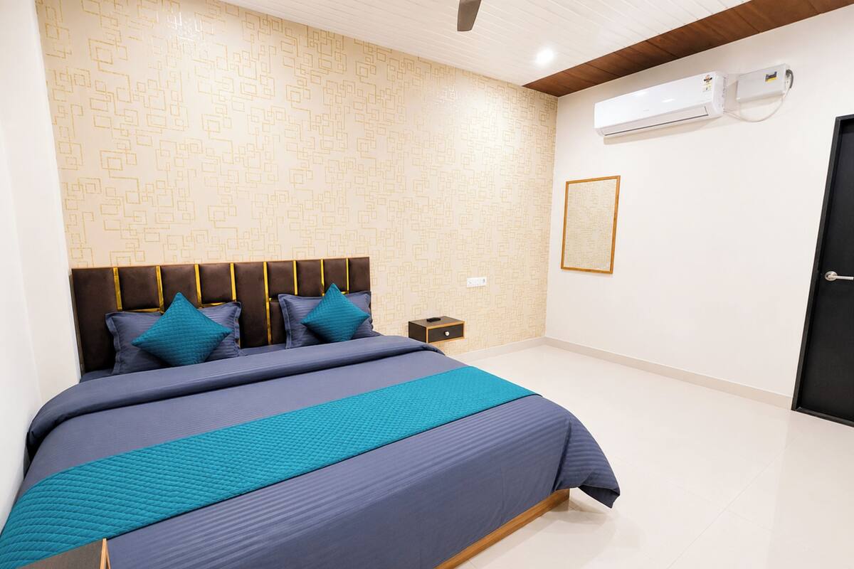 Un dormitorio con cama, mesita de noche, aire acondicionado instalado en la pared y una puerta.