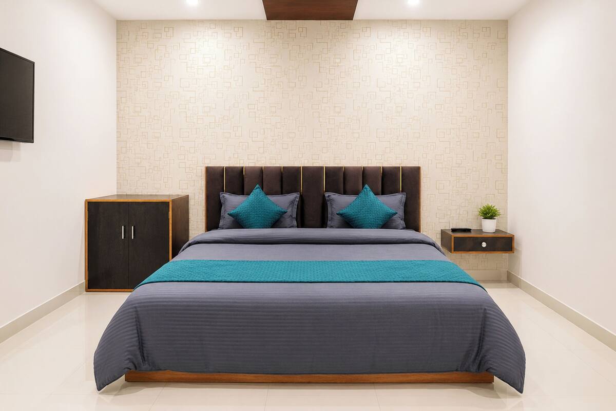 Un dormitorio moderno con una cama grande, cabecera, mesita de noche, televisión y pared con estampado.