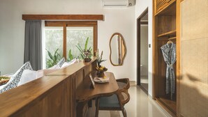 Una barra de madera con vistas a la vegetación exterior, un espejo y una bata colgada de una puerta de madera.