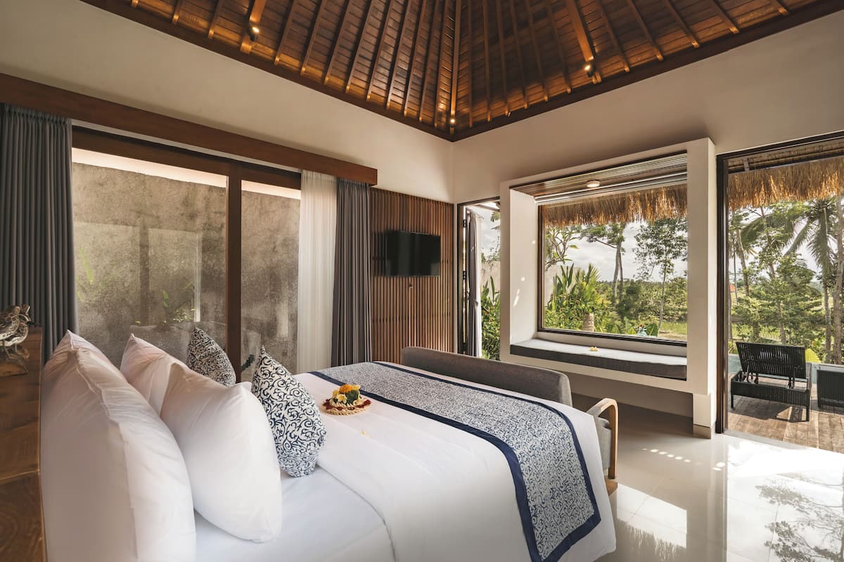Quarto moderno com uma cama grande, televisão e vista para o exterior.
