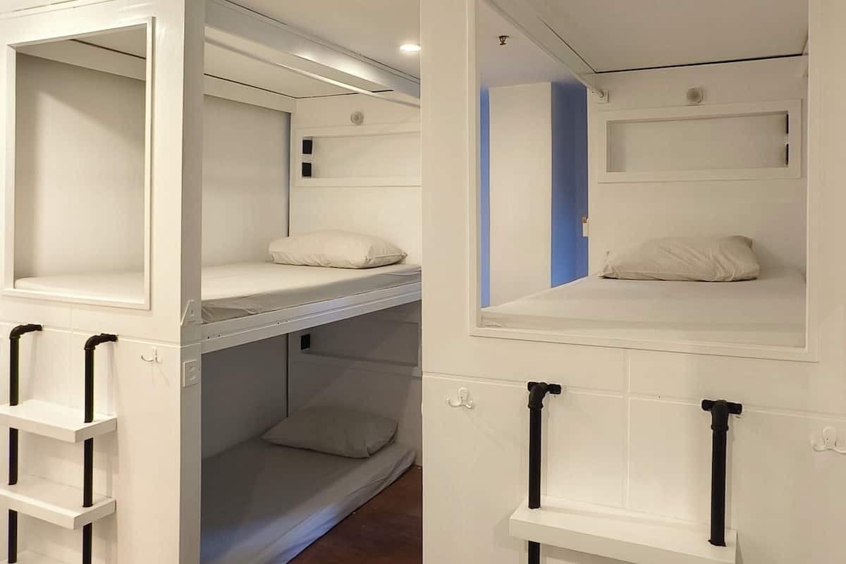 A bunk bed room with a white color scheme, a small window, and a door.